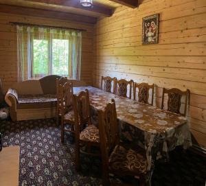 a dining room with a table and chairs in a cabin at Котедж Славний гуцул & СПА чани джакузі in Yablunytsya