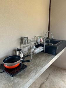 eine Küchentheke mit einer Bratpfanne und einem Spülbecken in der Unterkunft Rimtai Hütte in Mae Rim