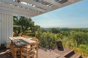 a wooden deck with a picnic table on the side of a house at Monte das Casolas in Grândola