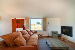 a living room with a brown couch and a tv at Monte das Casolas in Grândola
