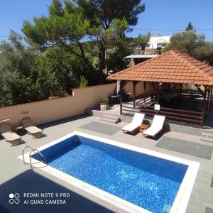 a swimming pool on a patio with chairs and a pavilion at Villa Aberdeen in Tivat