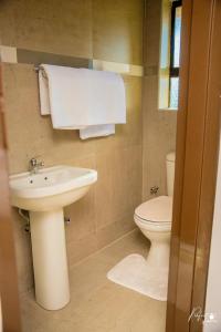 a bathroom with a sink and a toilet and towels at Northgate Villa Guest House in Gweru