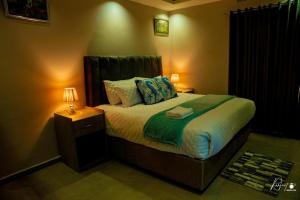 a bedroom with a bed and a night stand with a lamp at Northgate Villa Guest House in Gweru