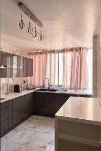 a kitchen with white counters and pink curtains at Appartement 3 pièces Nice-Ouest in Nice