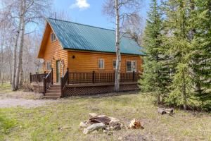 a log cabin with a green roof in the woods at The Aspen House in West Yellowstone