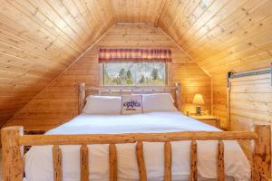 a bed in a wooden cabin with a window at The Aspen House in West Yellowstone