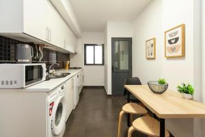 a kitchen with white appliances and a wooden table at Sea waves - Olhão in Olhão