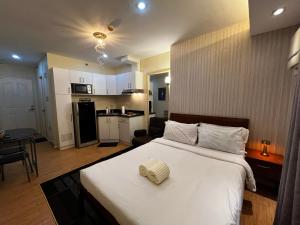 a bedroom with a large bed and a kitchen at Studio unit inside IT Park Wifi & Netflix in Cebu City