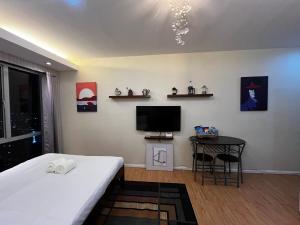 a bedroom with a bed and a tv and a table at Studio unit inside IT Park Wifi & Netflix in Cebu City