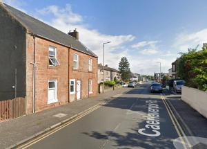 an empty street with cars parked on the side of the road at Garden Gate Upper Apartment in Prestwick