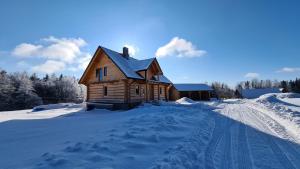 a log cabin in the snow with footprints in the snow at Drewniana chata in Cisówek
