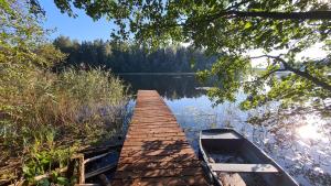 a boat is docked next to a dock on a lake at Drewniana chata in Cisówek +42 photos