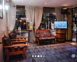 a living room with chairs and a tv and a couch at Nuevo Hotel Pacifico in Mendoza