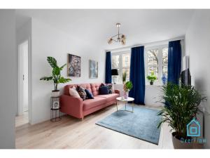 a living room with a pink couch and blue curtains at Exclusive Apartment at Old Town Gdansk in Gdańsk +4 photos