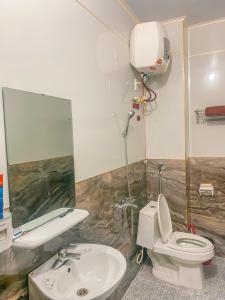 a bathroom with a toilet and a sink and a mirror at Nhà Của Mai in Mộc Châu