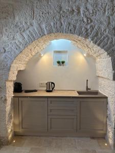 a kitchen with an arch in a stone wall at Il Trullo di Betta in Alberobello