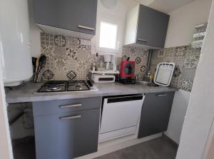 a small kitchen with a stove and a sink at chalet typique 50 m de la mer in Gruissan +10 photos