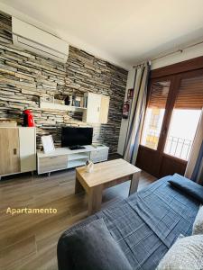 a living room with a stone wall and a tv at Descanso de Dulcinea in Almagro