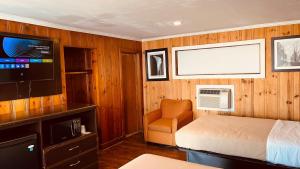 a bedroom with a bed and a chair and a tv at Richmond Motel in Richmond
