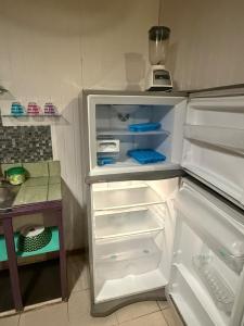 an empty refrigerator with its door open in a kitchen at Air conditioned home with full kitchen, TV and parking in Puerto Viejo