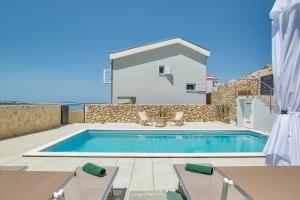ein Swimmingpool mit Stühlen und ein Haus in der Unterkunft Vila Bernarda by Resort Čulina in Metajna