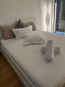 Una cama blanca con almohadas y una toalla. en Coqueto, en Ginebra