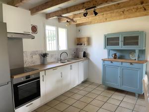 a kitchen with blue and white cabinets and a sink at Le Gîte de Julia in Saint-Laurent-de-Médoc