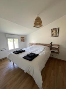 a bedroom with a white bed with two black towels on it at Le Gîte de Julia in Saint-Laurent-de-Médoc