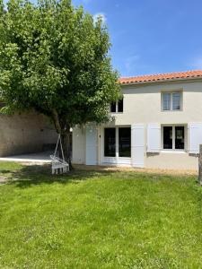a house with a tree in the yard at Le Gîte de Julia in Saint-Laurent-de-Médoc