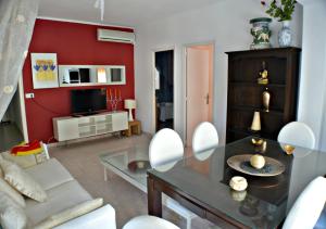 sala de estar con mesa y pared roja en Apartamentos de las Heras, en Ibiza