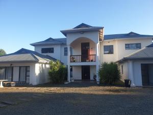 a large white house with a balcony on top at Mountain View Guest House in Underberg in Underberg