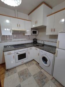 a kitchen with white cabinets and a sink and a dishwasher at Apartamento la Costa in Colunga