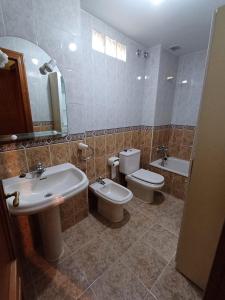 a bathroom with two sinks and a toilet and a mirror at Apartamento la Costa in Colunga