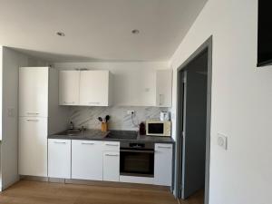 a kitchen with white cabinets and a microwave at Chaleureux studio central Appart B in La Roche-sur-Yon