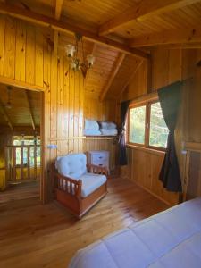 a bedroom with a couch in a room with wooden walls at Chalés Sol da Serra in Rio Rufino