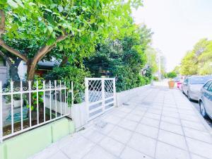 a white fence on a sidewalk next to a tree at Spacious 2BR by Floisvos Beach Saltwater Balcony in Athens