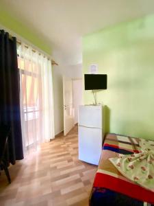 a room with a white refrigerator and a television at Vila Brahimasi in Durrës