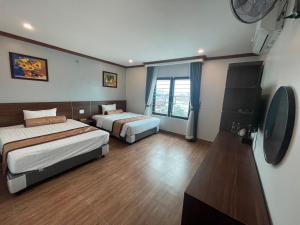 Una habitación de hotel con dos camas y un televisor. en A&E hotel2, en Qua Phố