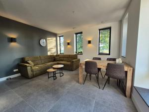 un soggiorno con un divano, un tavolo e delle sedie di Vakantiewoning OpdeBaan a Kaatsheuvel Altre 16 foto