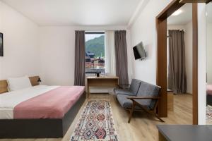 a hotel room with a bed and a chair and a window at 3100 Boutique Hotel Kazbegi in Kazbegi