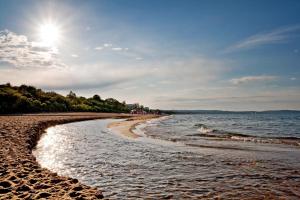a beach with the sun shining on the water at Apartament Morze Bałtyckie in Gdańsk