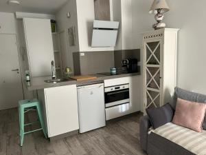 a small kitchen with white cabinets and a couch at Loft Barbate in Barbate