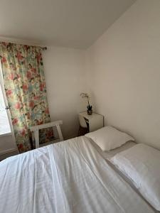 ein Schlafzimmer mit einem weißen Bett und einem Fenster in der Unterkunft Chambre à 20 minutes de Paris NOTRE DAME, APPARTEMENT COMMUN in Épinay-sur-Seine