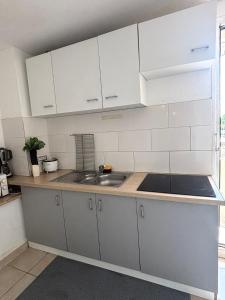 eine Küche mit weißen Schränken und einer Spüle in der Unterkunft Chambre à 20 minutes de Paris NOTRE DAME, APPARTEMENT COMMUN in Épinay-sur-Seine