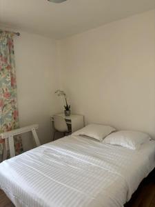 ein weißes Bett mit zwei Kissen und einem Tisch in der Unterkunft Chambre à 20 minutes de Paris NOTRE DAME, APPARTEMENT COMMUN in Épinay-sur-Seine