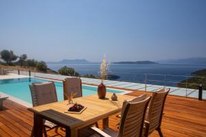 a wooden table and chairs on a deck with a pool at 2S Villas Resort - Cave Villas in Sivota