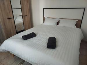 ein weißes Bett mit zwei schwarzen Hüten darauf in der Unterkunft petite maison lavardac in Lavardac