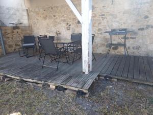 eine Holzterrasse mit Stühlen und einem Tisch und einem Grill in der Unterkunft petite maison lavardac in Lavardac