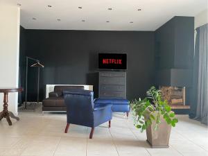 a living room with a tv and a blue chair at Sea view apartment in Kavála