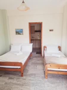 two beds sitting in a room with a door at Anastasia Chalatsogianni Rooms in Paralia Panteleimonos